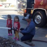 Fireman showing toddler twins the fire hose