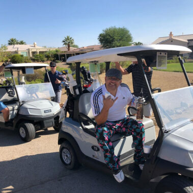 Guys in the golf cart with posing with liquor bottle