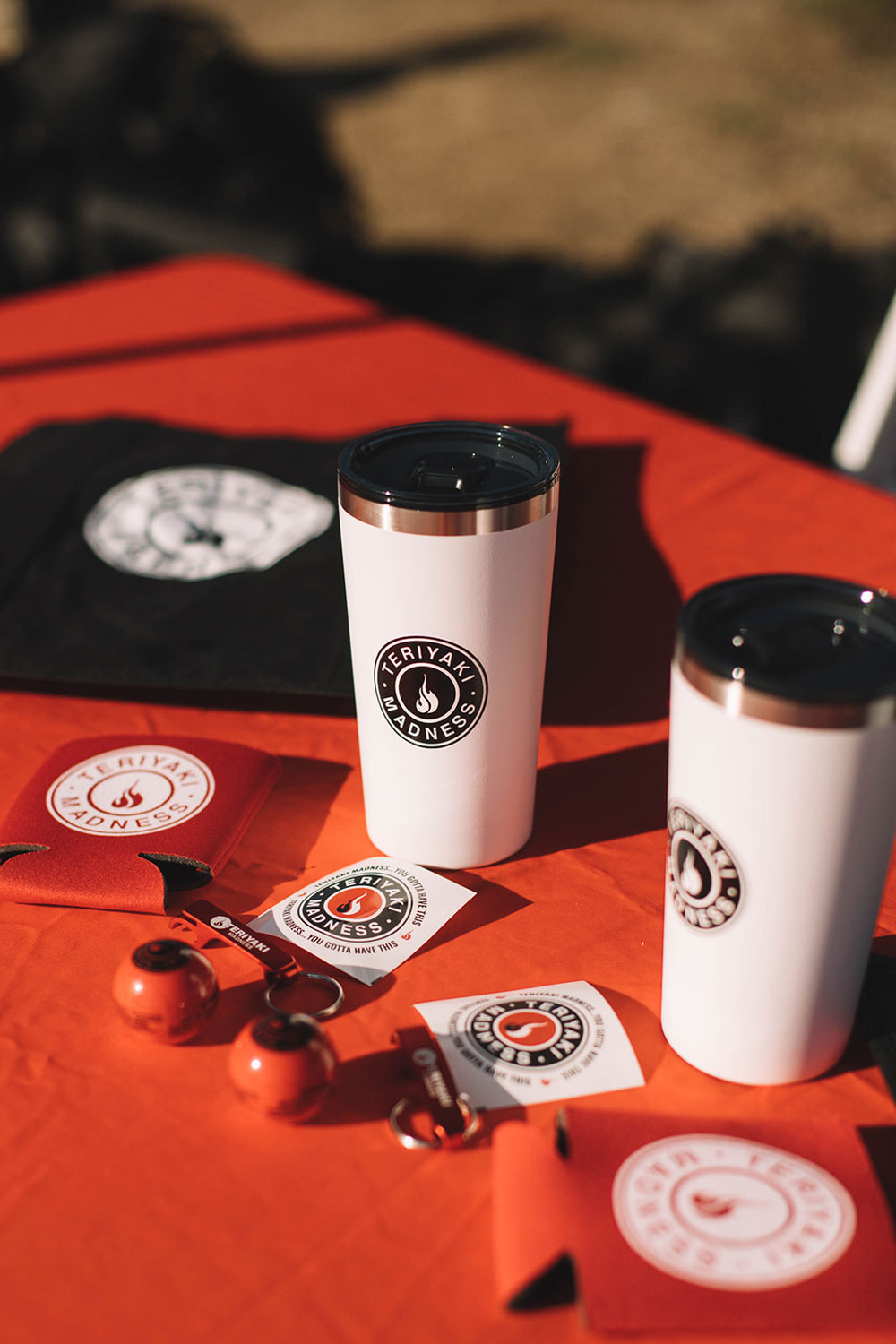 Teriyaki Madness promotional items, coffee tumblers, stickers, and t-shirts