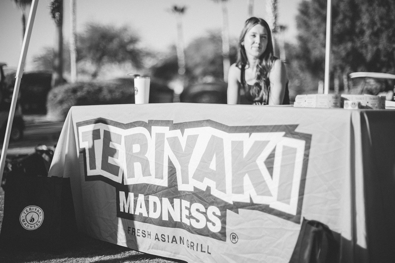 Teriyaki Madness Fresh Asian Grill booth with lady sitting behind the table in black and white
