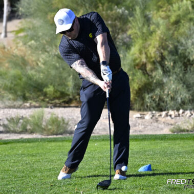 Male golfer swinging at golf ball.