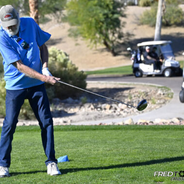 Male golfer swinging at golf ball.