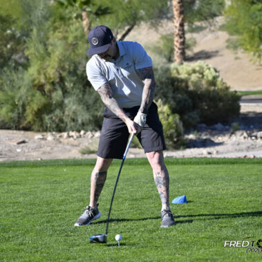 Male golfer swinging at golf ball.