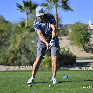 Male golfer swinging at golf ball.