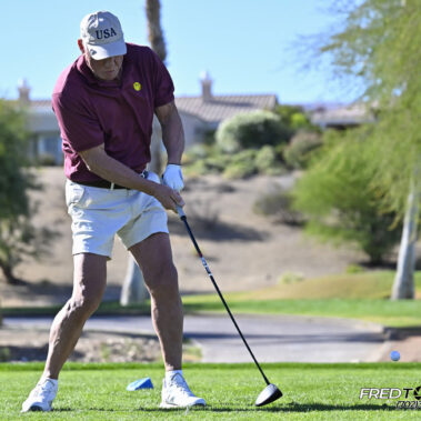 Male golfer swinging at golf ball.
