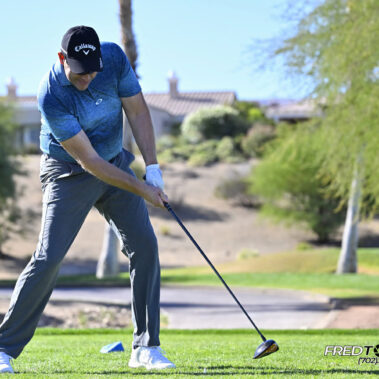 Male golfer swinging at golf ball.