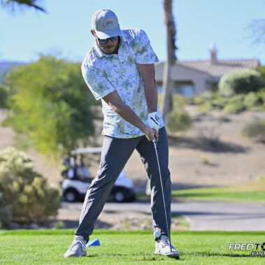 Male golfer swinging at golf ball.