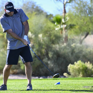 Male golfer swinging at golf ball.