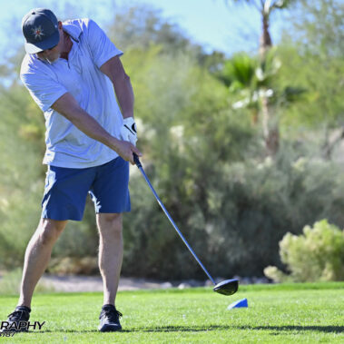 Male golfer swinging at golf ball.