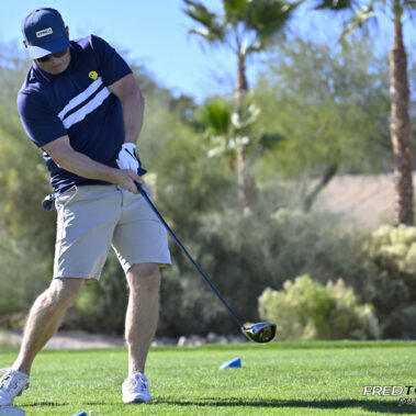 Male golfer swinging at golf ball.
