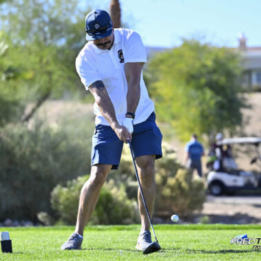 Male golfer swinging at golf ball.