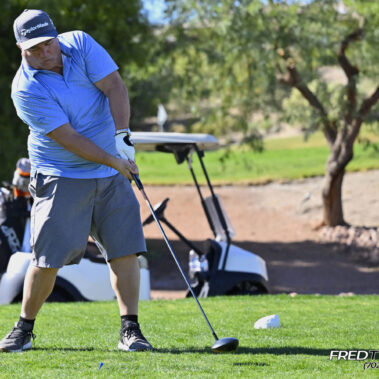 Male golfer swinging at golf ball.