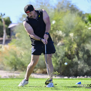 Male golfer swinging at golf ball.
