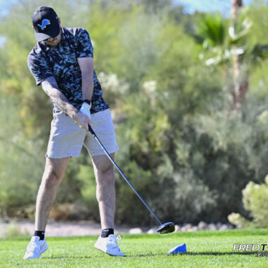 Male golfer swinging at golf ball.