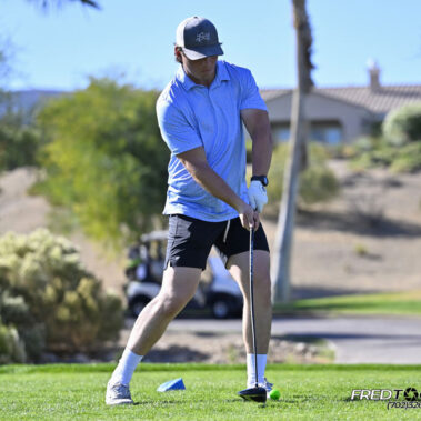Male golfer swinging at golf ball.