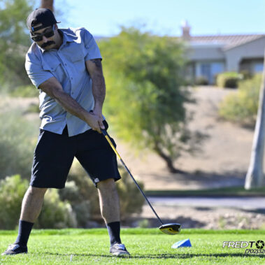 Male golfer swinging at golf ball.