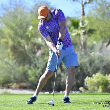 Male golfer swinging at golf ball.