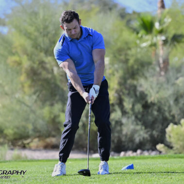 Male golfer swinging at golf ball.
