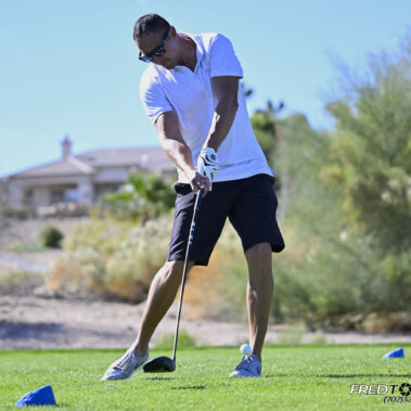 Male golfer swinging at golf ball.