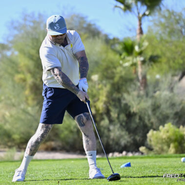 Male golfer swinging at golf ball.