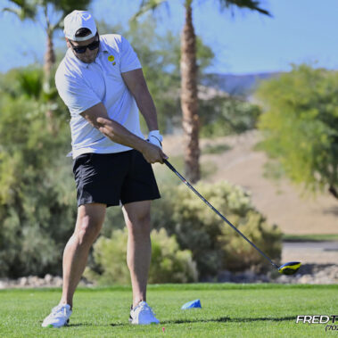 Male golfer swinging at golf ball.