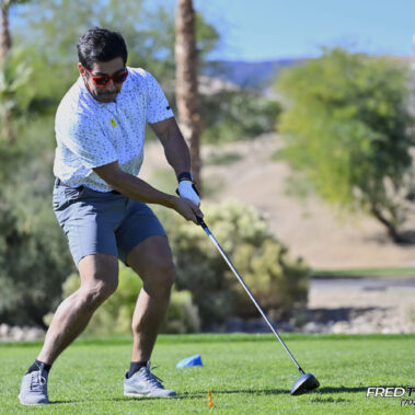 Male golfer swinging at golf ball.