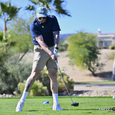 Male golfer swinging at golf ball.