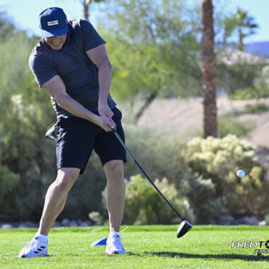 Male golfer swinging at golf ball.