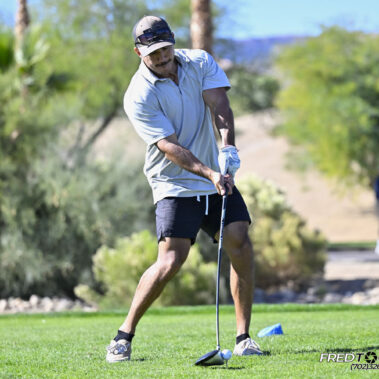 Male golfer swinging at golf ball.