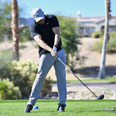 Male golfer swinging at golf ball.