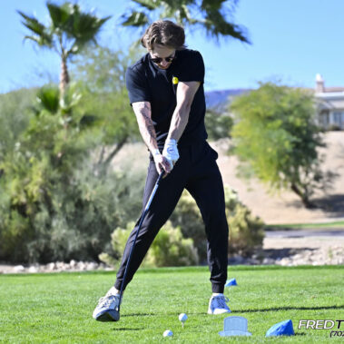 Male golfer swinging at golf ball.
