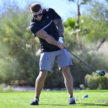 Male golfer swinging at golf ball.