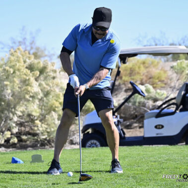 Male golfer swinging at golf ball.