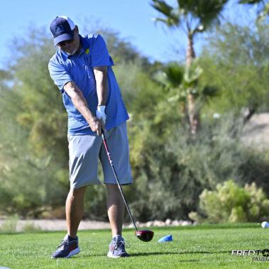 Male golfer swinging at golf ball.