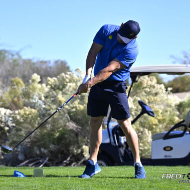 Male golfer swinging at golf ball.