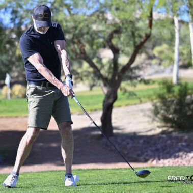 Male golfer swinging at golf ball.