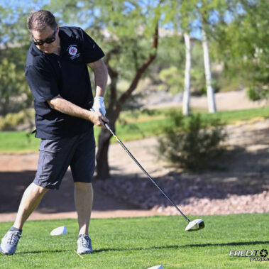 Male golfer swinging at golf ball.