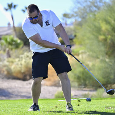 Male golfer swinging at golf ball.
