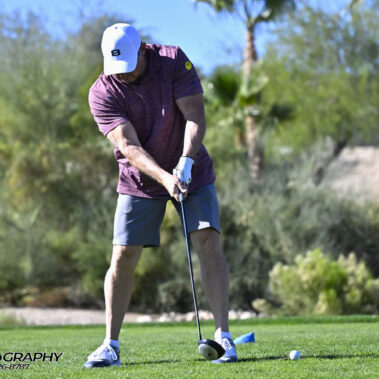 Male golfer swinging at golf ball.
