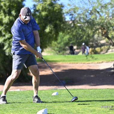 Male golfer swinging at golf ball.