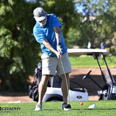 Male golfer swinging at golf ball.