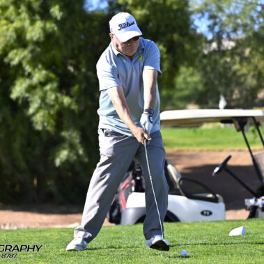Male golfer swinging at golf ball.