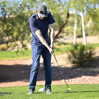 Male golfer swinging at golf ball.