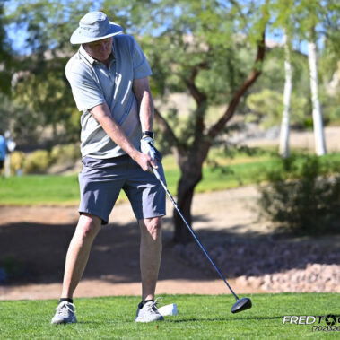 Male golfer swinging at golf ball.