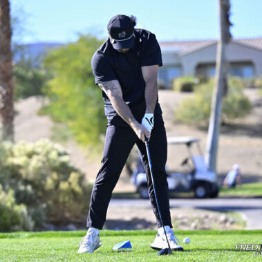 Male golfer swinging at golf ball.