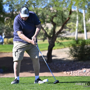 Male golfer swinging at golf ball.