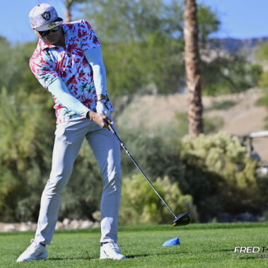 Male golfer swinging at golf ball.