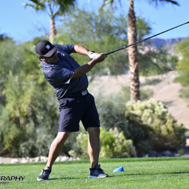 Male golfer swinging at golf ball.