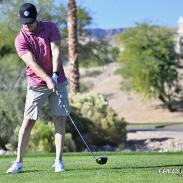Male golfer swinging at golf ball.