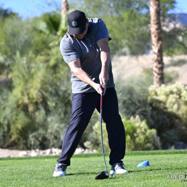 Male golfer swinging at golf ball.